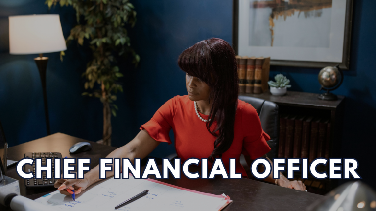Black woman in red dress working at a desk with a calendar and computer — representing a fractional CFO providing strategic financial planning and growth support for small businesses.