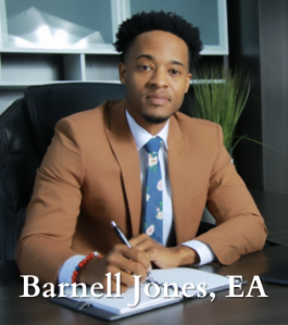 Man in brown suit sitting at desk.